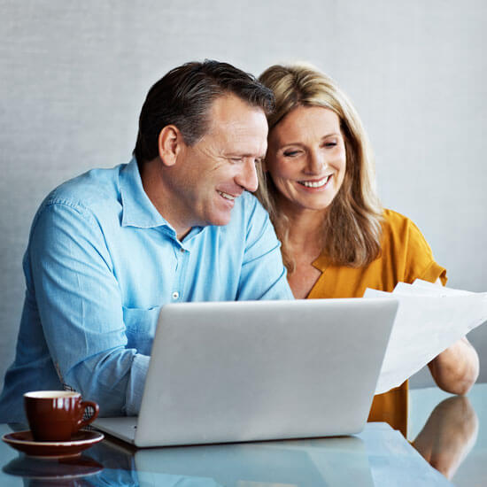 a couple is looking at papers in front of computer