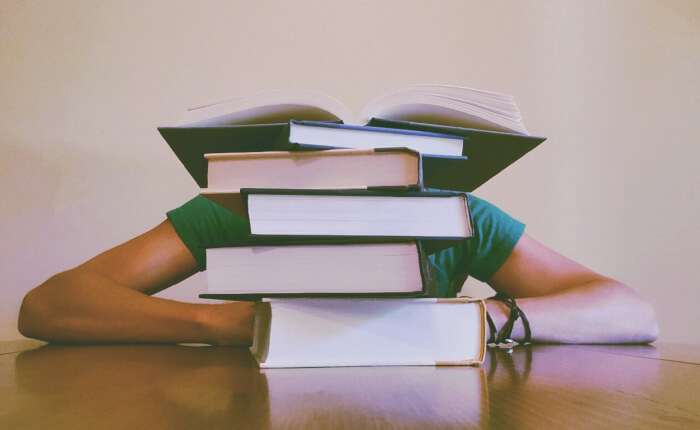 person behind stack of books studying history of dental hygiene