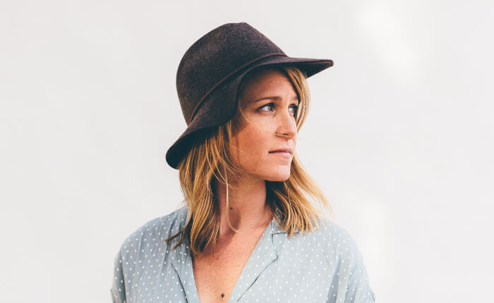 Headshot of blonde woman wearing a dark hat looking off to the side wondering if she should get her wisdom teeth removed