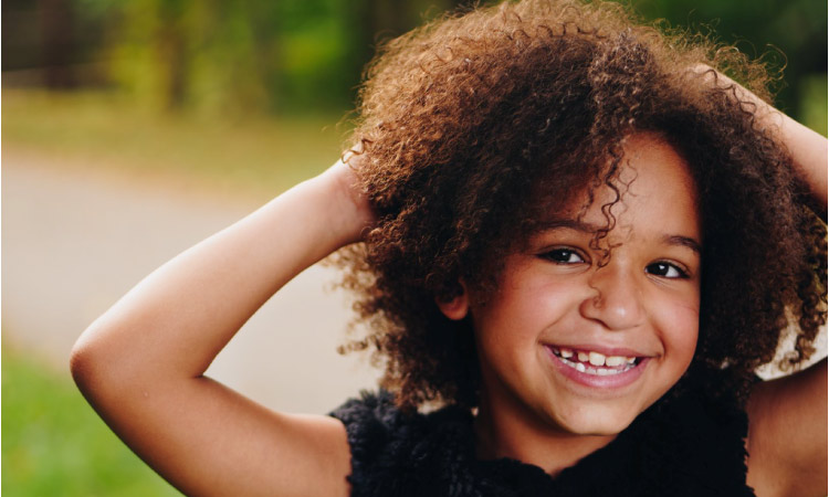 young girl smiling holding her head