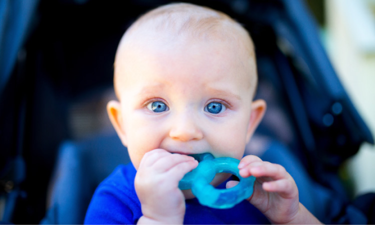 blue eyed baby boy teething chewing on a blue toy