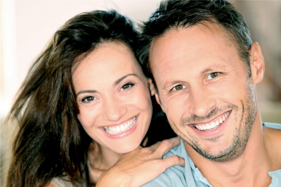 young couple smile to show off their porcelain veneers