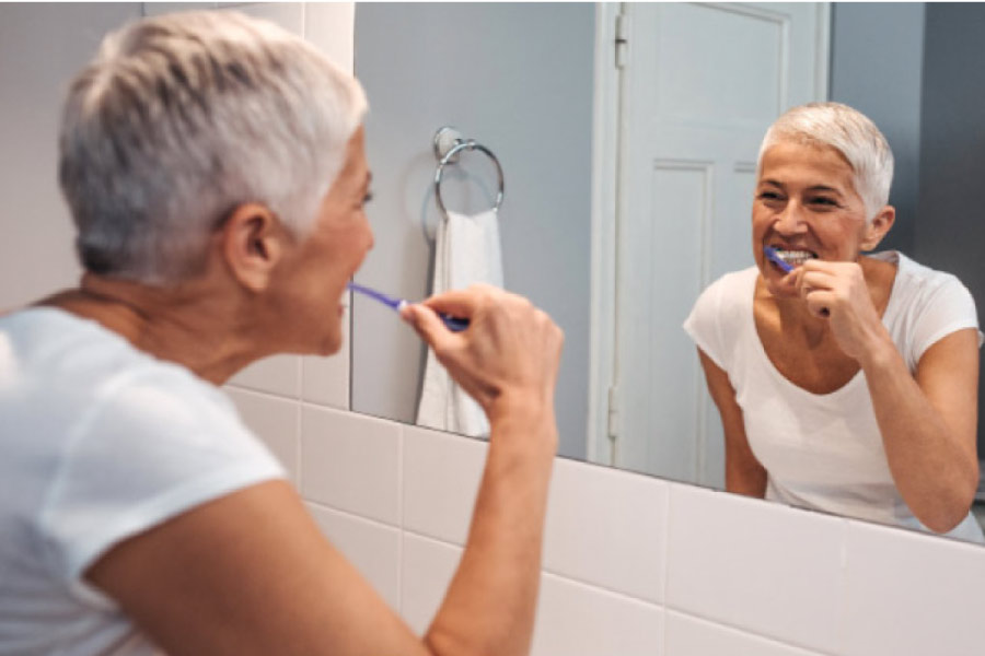 woman looks in the bathroom mirror and brushes her teeth